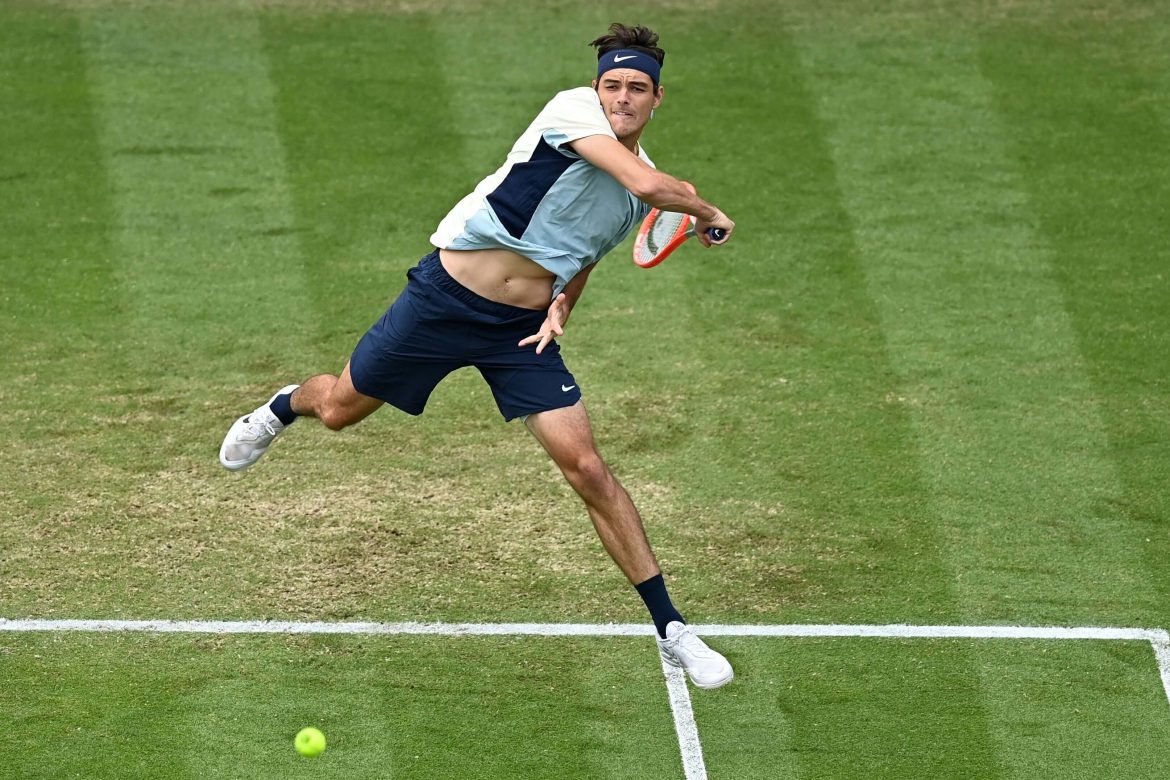 Taylor Fritz, in white and black uniform, returns a shot in this file photo. Fritz moved up to the top 10 in the recent ATP rankings