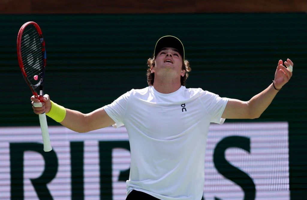 Braziliabn Joao Fobnseca raises his arms inb celebration during his first round match at the BNP Paribas Open obn Thursday. Indian Wells openers see Raducanu lose; Fonseca advances