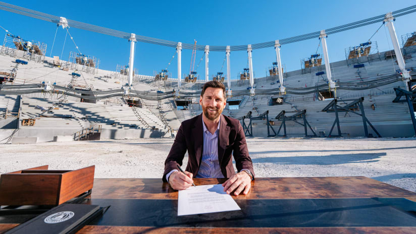 Lionel Messi re-signs with Inter-Miami, posing for a photo after he signs his contract extension that would push his new deal until after the 2028 MLS season