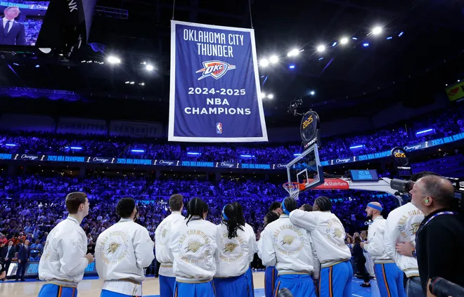 Players from OKC look up as the team's championship banner is raised and unveiled during a ring ceremony hours before the Rockets vs Thunder match.